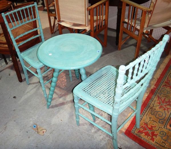 A pair of blue painted faux bamboo chairs and a circular table.