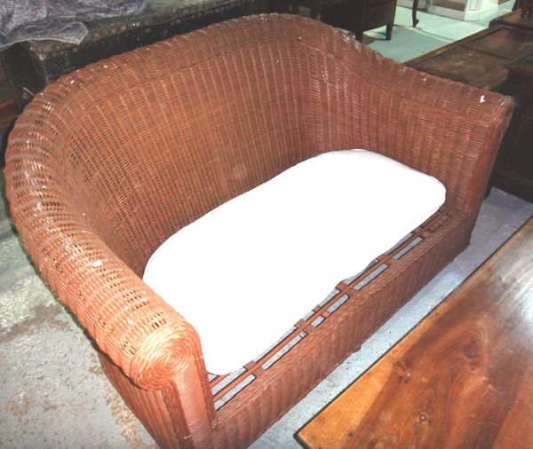 A 20th century wicker two seat sofa with cream upholstered cushion.