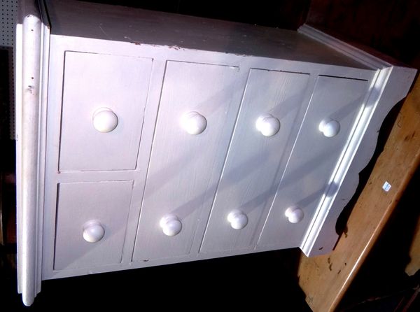 A small white painted bedside chest of two short and three long drawers.