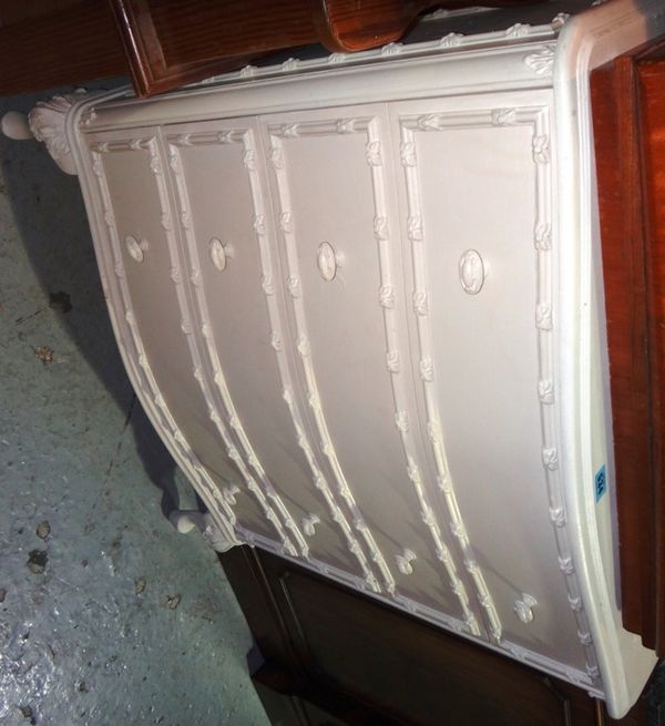A white painted chest of four drawers with carved decoration.
