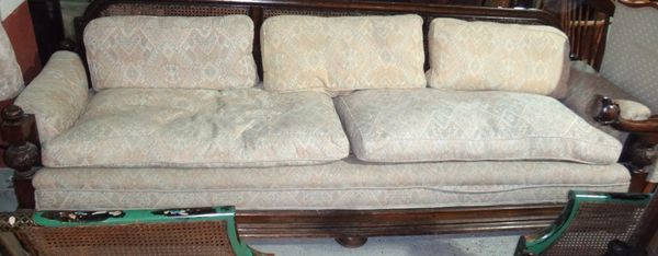A large 20th century oak framed bergere sofa with carved decoration.
