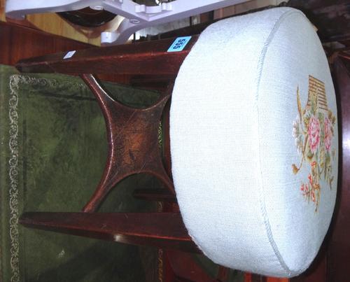 A 19th century mahogany stool with a green and floral needlework upholstered seat.