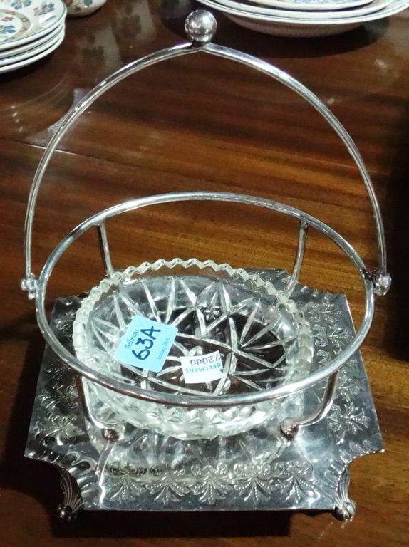 A silver plated basket with swing handle, foliate engraving and shell cast feet, with cut glass bowl.
