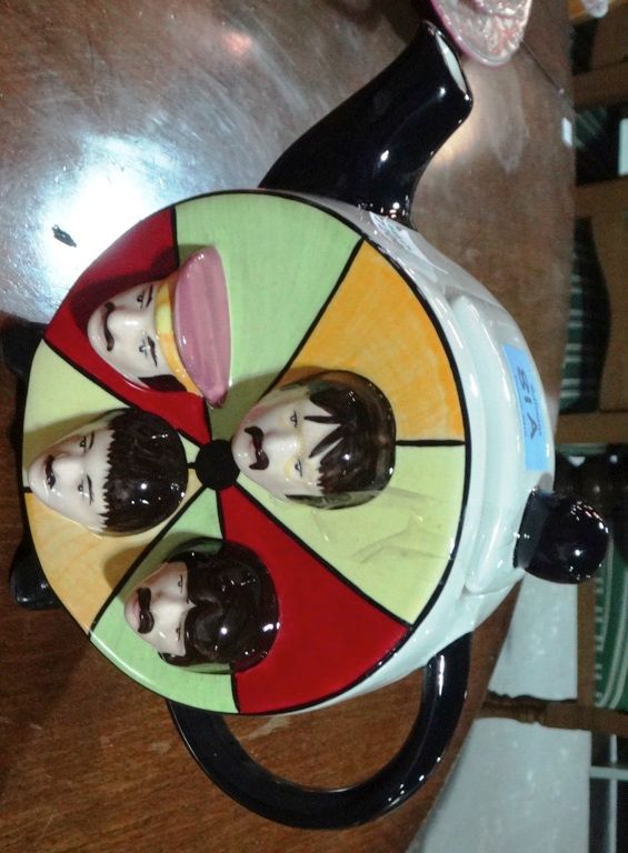 A pottery teapot modelled as a drum with portraits in relief of The Beatles, by Lorna Bailey.