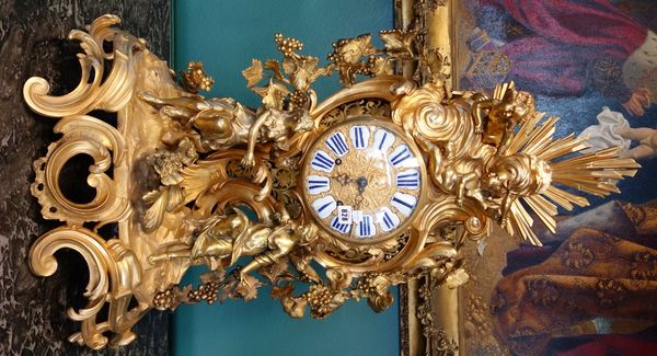 A French ormolu mantel clock of large proportions, circa 1900, ornately cast with figures and cherubs against a bocage of fruiting vines, the dial pla