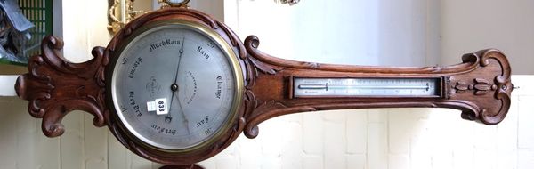 A Victorian oak cased wheel barometer, with all over foliate carving and applied thermometer, over a ten inch silvered dial detailed 'Frankham & Wilso