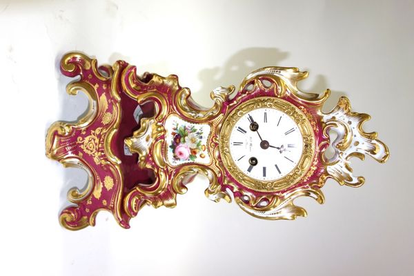 A French porcelain mantel clock, late 19th century, with gilt and burgundy scroll work case enclosing an enamel dial detailed 'Hry Marc a Paris' and a