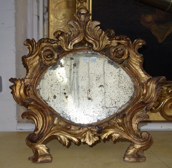 An early 19th century mirror, the bevelled shaped plate with wide Continental silver embossed border, 53cm, and a gilt wood strut back mirror of Rococ