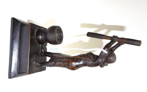 A bronze figure, late 19th/early 20th century, modelled and cast as a woman in traditional dress with a large pestle and mortar, mounted on an ebonise