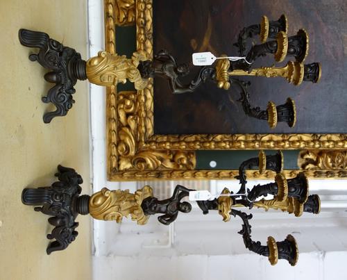 A pair of patinated and gilt bronze four branch figural candelabrae, early 20th century, modelled and cast with opposing male and female figures, hold