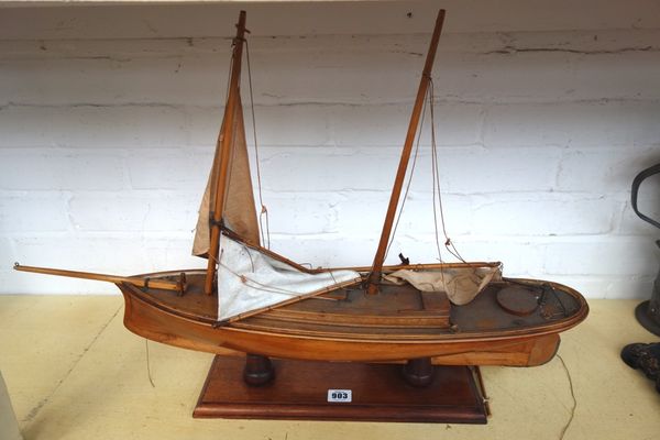 A wooden model sailing boat with shaped wooden keel and metal mounted rudder, on a wooden stand, 73cm wide.