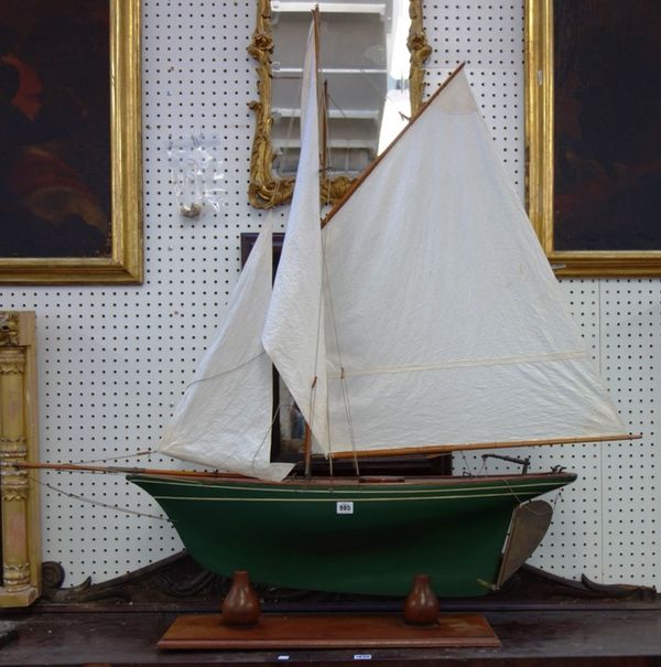 A wooden model boat, fully rigged with green painted hull and gilt metal rudder, on a mahogany stand, 115cm wide.