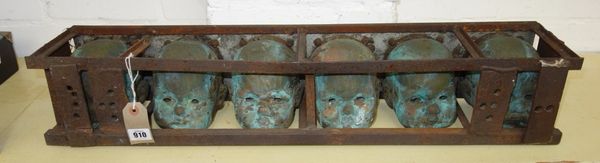 A patinated iron art installation modelled as six dolls heads in an iron box, 77cm wide.