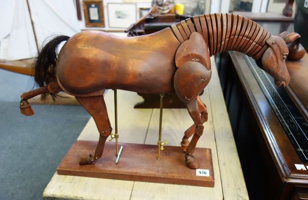 A modern hardwood model of an articulated horse, raised on a mahogany plinth, approximately 50cm wide.