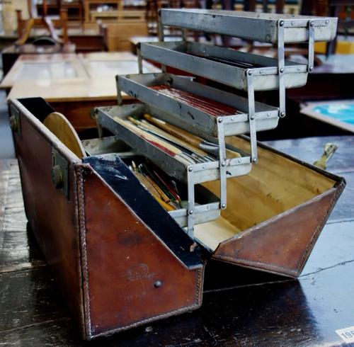 An artist's leather travel case, with brass hardware and fitted interior enclosing a quantity of paintbrushes and related equipment.