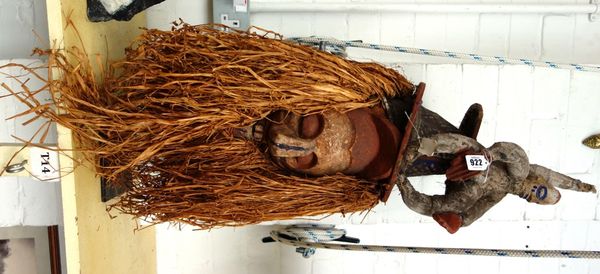 An African tribal mask, late 20th century, polychrome painted with straw for hair and beard, raised on a metal display stand, the mask approximately 7