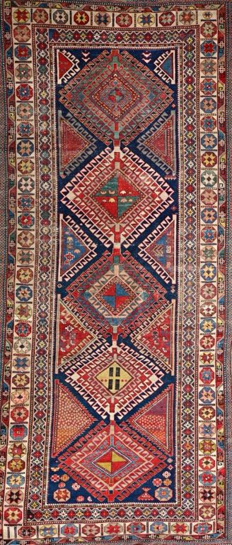 A Shirvan runner, Caucasian, the indigo field with five bold hooked diamonds, supporting motifs, an ivory star border, 314cm x 134cm.  Illustrated