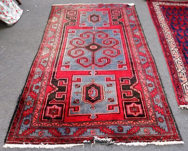 A Hamadan rug, Persian, the madder field with one large and two smaller grey square medallions, a leaf border, 224cm x 128cm.