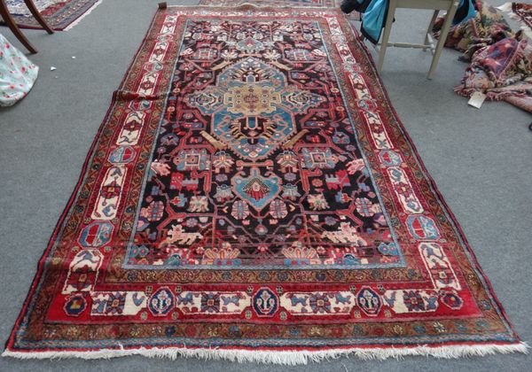 A Bakhtiari rug, Persian, the black field with a bold indigo medallion, all with angular vines, a madder ivory cartouche border, 290cm x 155cm.