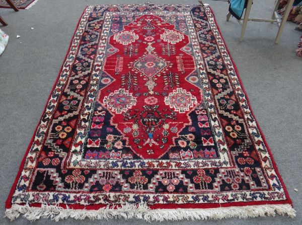 A Hamadan rug, Persian, the madder field with a central medallion, a lantern at each end, four single medallions, a black flower and leaf border, 235c
