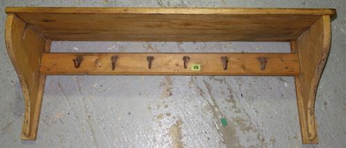 A pine wall mounted coat rack with shelf and six hooks, 100cm long.