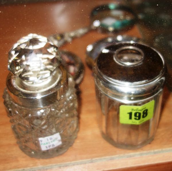A group of silver mounted wares, comprising; a silver rimmed cut glass toilet bottle, a silver lidded faceted glass hair tidy, two photo frames and a