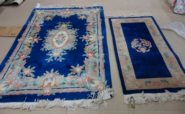 Two Chinese rugs with indigo fields and ivory flower borders, 147cm x 69cm and 183cm x 121cm. (2)