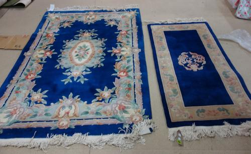 Two Chinese rugs with indigo fields and ivory flower borders, 147cm x 69cm and 183cm x 121cm. (2)