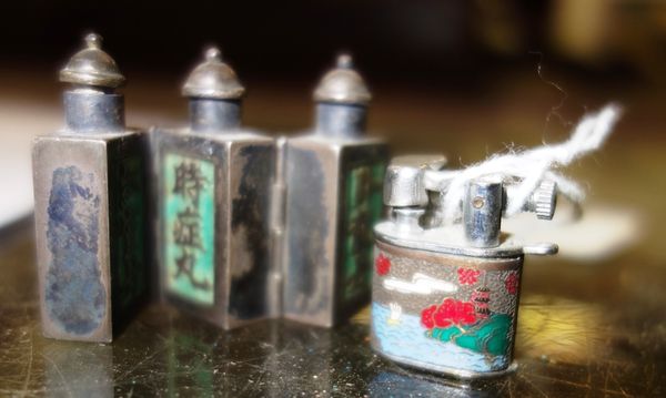 A miniature Chinese metal triptych scent bottle decorated with characters and a miniature lighter marked 'pygmy'.