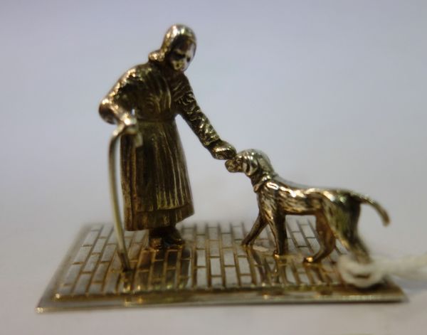 A continental silver small model of a dog and an elderly lady on a cobbled street, import mark for Dublin 1954, 4.5cm long.