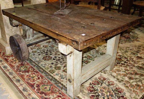 A 20th century hardwood coffee table formed as a trolley with iron wheels, 112cm wide.