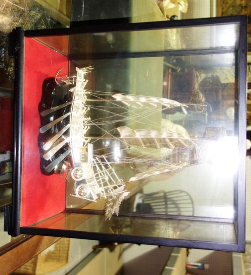 A 20th century Oriental white metal model of a boat in an ebonised glazed case.