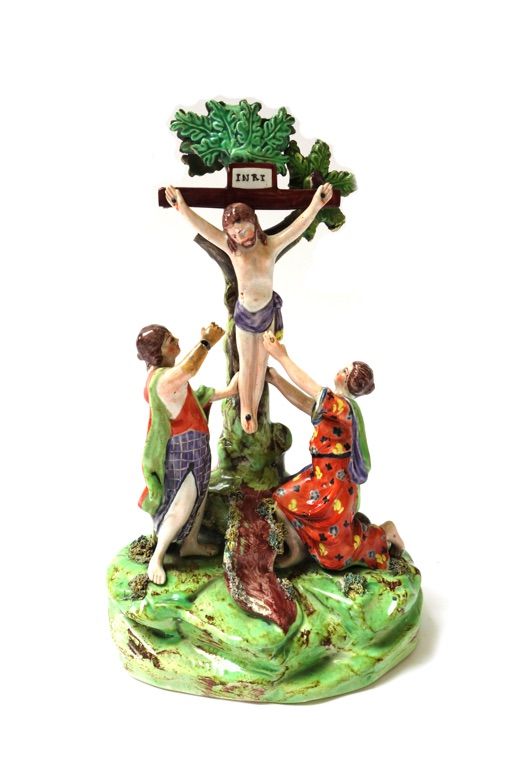 A Staffordshire pearlware crucifixion group, circa 1820, modelled with Mary and St. John beneath the cross, on a grassy mound base (a.f.), 26cm.high.