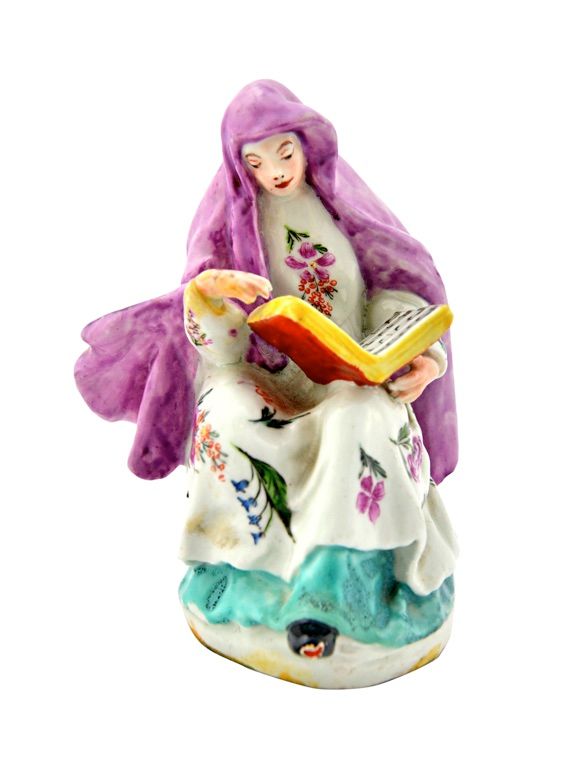 A Chaffer's Liverpool figure of a nun, circa 1756-58, modelled seated with a book of sheet music, probably decorated in London, wearing a puce veil, w