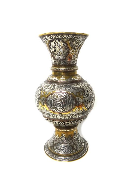An Islamic silvered and brass pierced lamp, late 19th/early 20th century, of baluster form, pierced with foliate panels and engraved with barbed panel