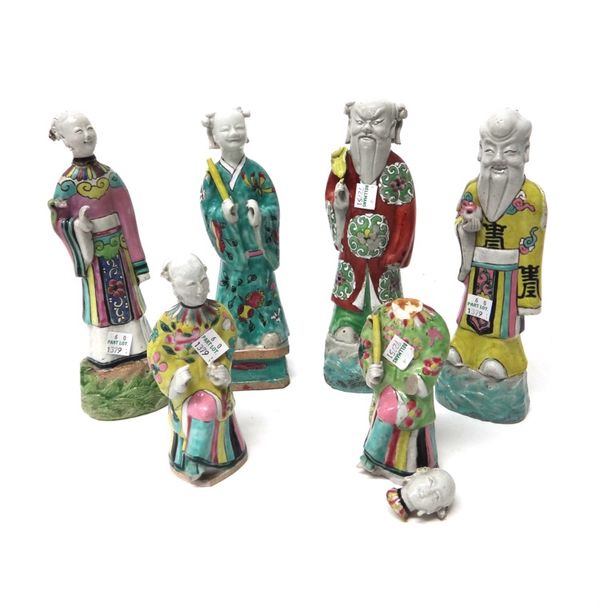 A group of four Chinese famille rose figures of standing Immortals, late 18th/19th century, on wave-pattern or rectangular  bases, each holding an att