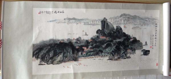 A Chinese scroll painting , depicting a rocky island with a coastline in the distance, 67cm. by 135cm., boxed.