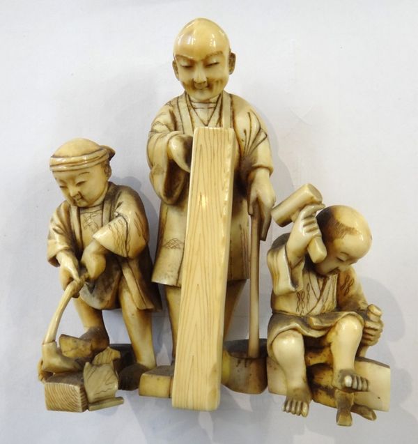 A Japanese ivory group of three woodsmen, Meiji period, carved as a man and two boys at work, 10cm. high.