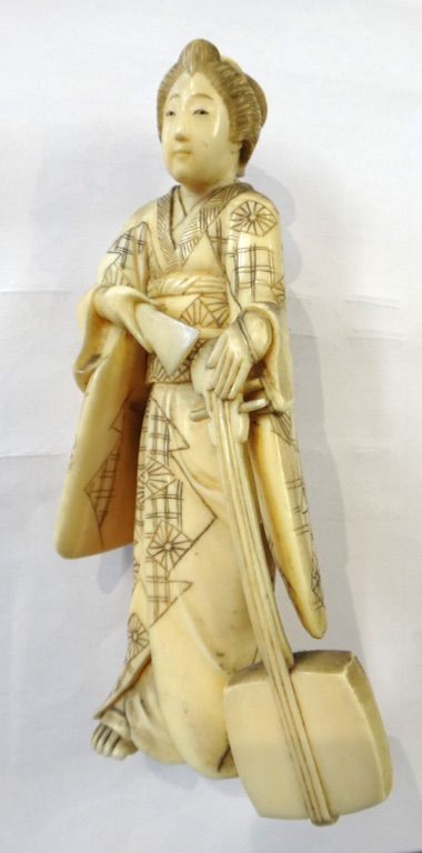 A Japanese ivory okimono of a bijin, Meiji period, standing in long robes holding a samisen in her left hand, 13cm.high; also a small Chinese ivory fi