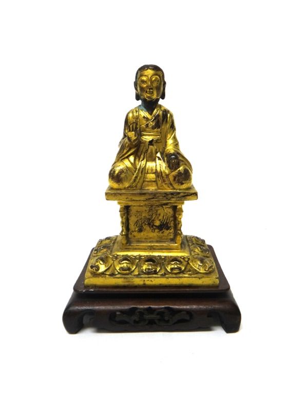 A gilt-metal figure of Buddha , seated with right hand raised in abhaya mudra, on a rectangular plinth engraved at the front with a figure leading a h