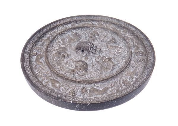 A Chinese bronze `lion and grapevine' mirror, possibly Tang Dynasty, cast with a frieze of birds and animals amongst fruiting vine, the centre with si