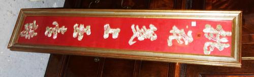 A Chinese embroidered wedding couplet, 20th century, worked with floral characters against a red ground, 98cm x 15cm, framed and glazed. (1)