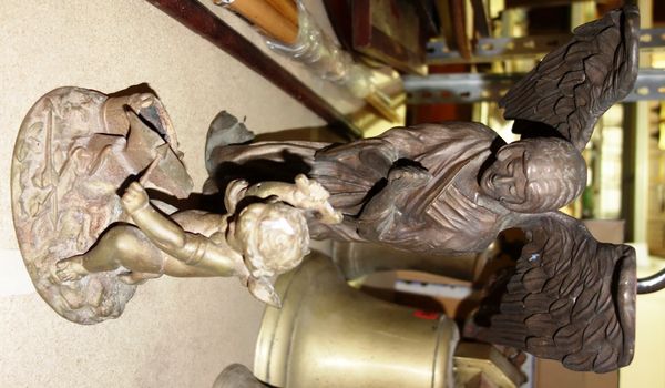 A 20th century cast bronze figure of a praying angel, together with another depicting a putto as a blacksmith. (2)