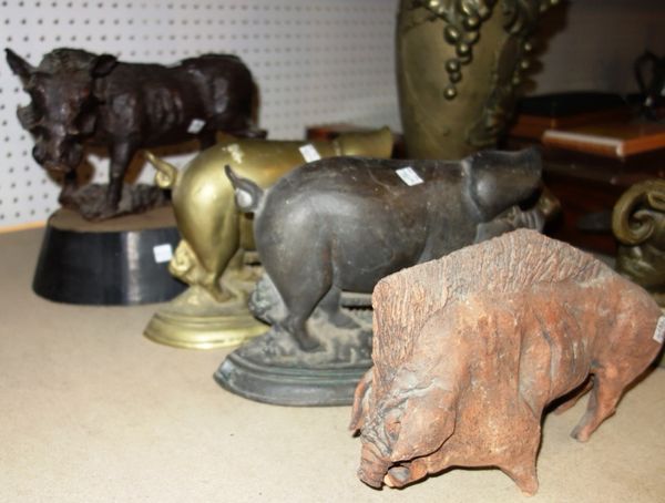 A 19th century carved oak figure of a boar on an associated ebonised base, together with a pottery model of a pig, and two metal doorstops formed as p