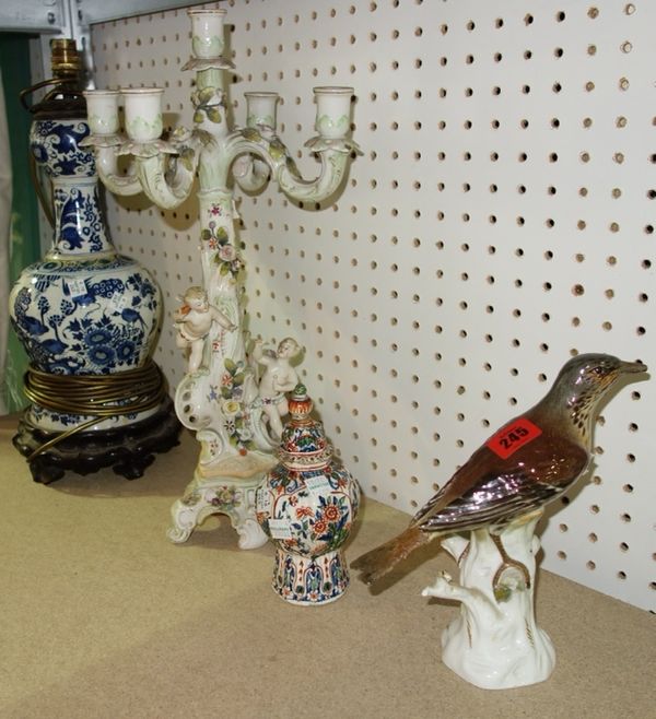 A Meissen ceramic model of a thrush (a.f), together with a small Delft vase and cover, a German porcelain candelabrum and a pottery lamp stand. (4)