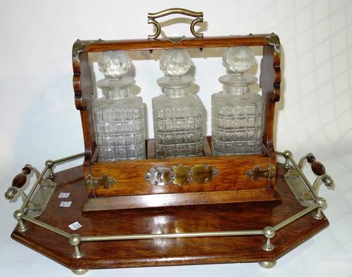 A 20th century oak three bottle tantalus, together with an oak and metal mounted tray. (2)