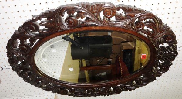 A carved oak oval wall mirror,64cm x 86cm.