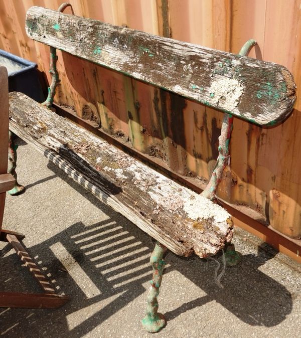 A green painted garden bench of naturalistic form.