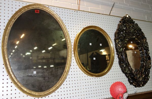A 19th century gilt framed oval wall mirror, 72cm wide, together with another, 48cm wide and a hardwood carved mirror, 49cm wide. (3)