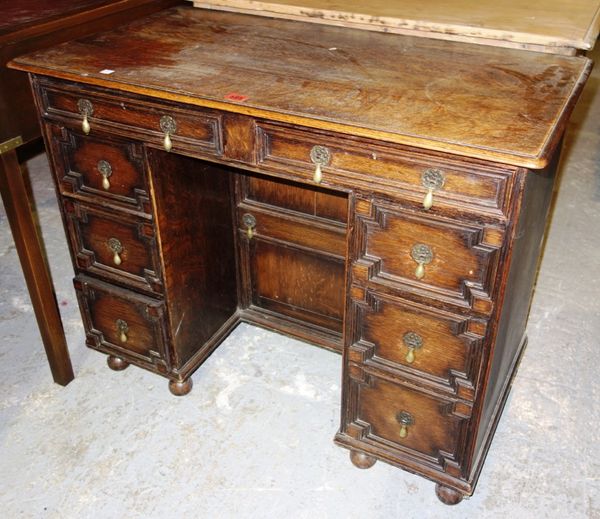 A 20th century oak kneehole desk with eight drawers about the knee and recessed central cupboard, 91cm wide.